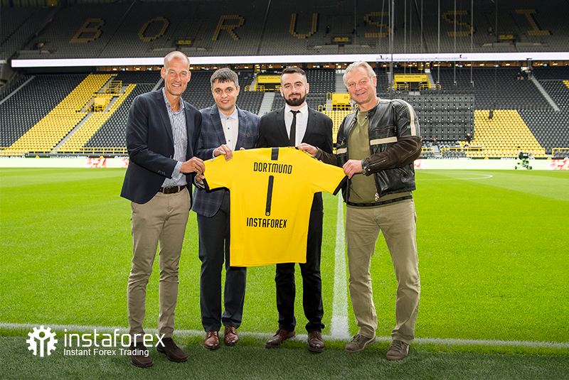 La leyenda de Borussia Dortmund Wolfgang de Beer, Director de Desarrollo de Negocios para InstaForex Pavel Shkapenko, Director de desarrollo de negocios de InstaForex para Asia Roman Tcepelev y CEO de Borusssia Carsten Cramer sostienen la camiseta simbólica de Borussia e Instaforex frente al campo de Singal Iduna Park Stadium